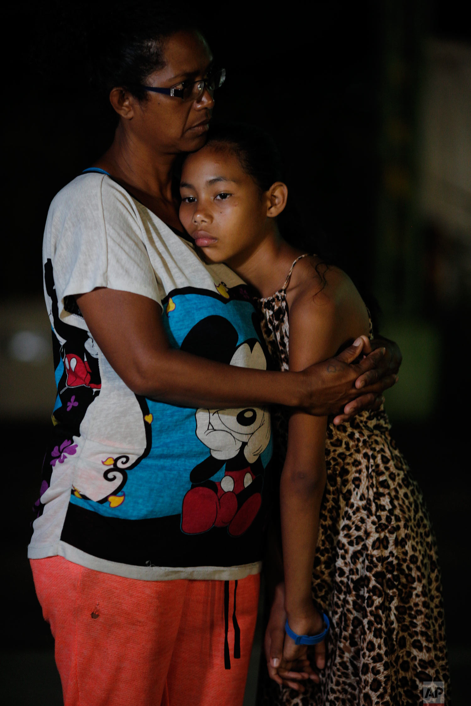  In this Sept. 4, 2018 photo, Venezuelan Sandra Cadiz and her 10-year-old daughter Angelis embrace after spending the night outside a Biomax gas station in a remote stretch of farmland known only as “Kilometer 17” in Santander state, Colombia, on the