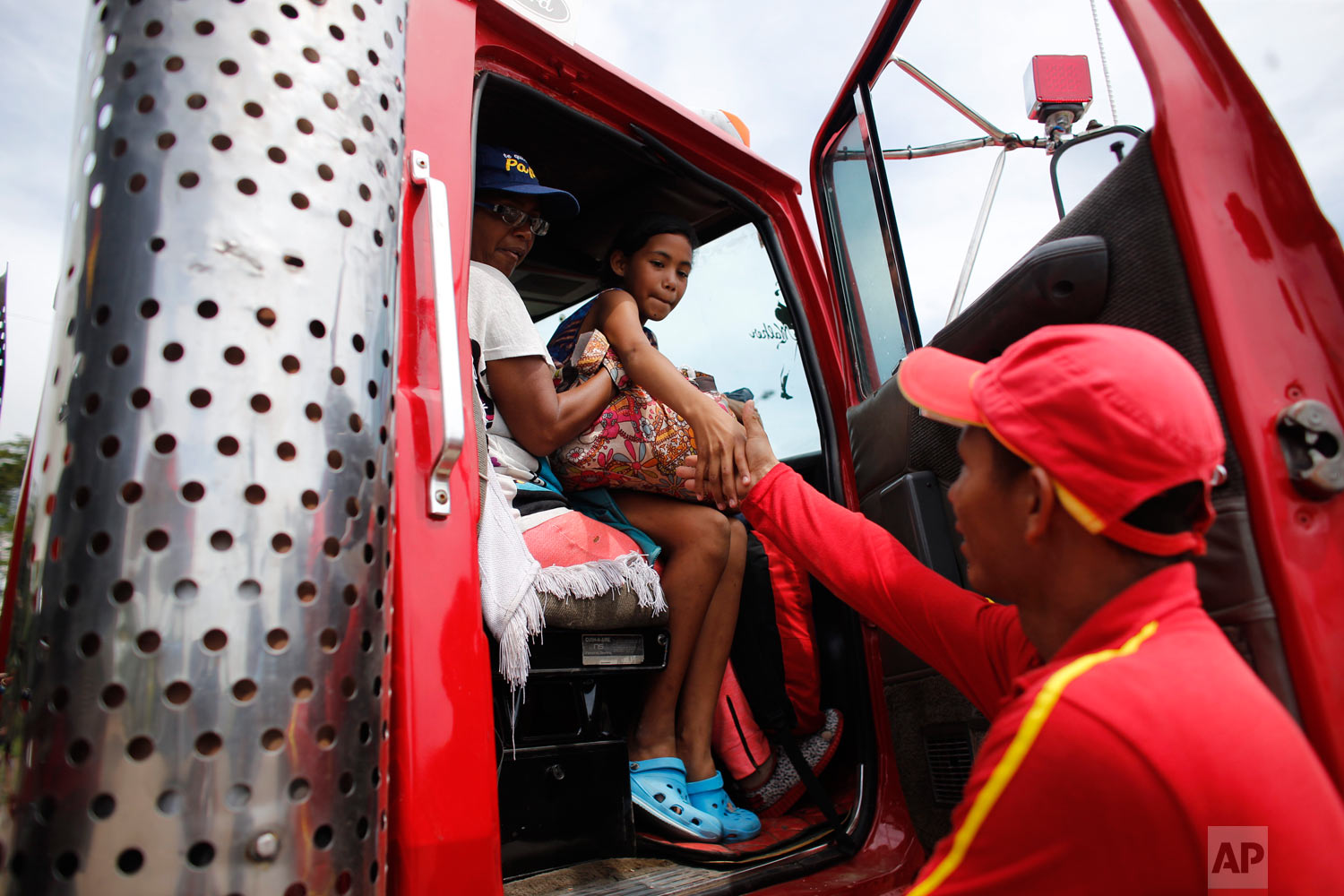  In this Sept. 3, 2018 photo, Venezuelan Sandra Cadiz and her 10-year-old daughter Angelis, thank gas station worker Manuel Velasquez after he helped them get a ride in the cabin of a truck in Peroles, Colombia, on their journey to Peru. Whenever the