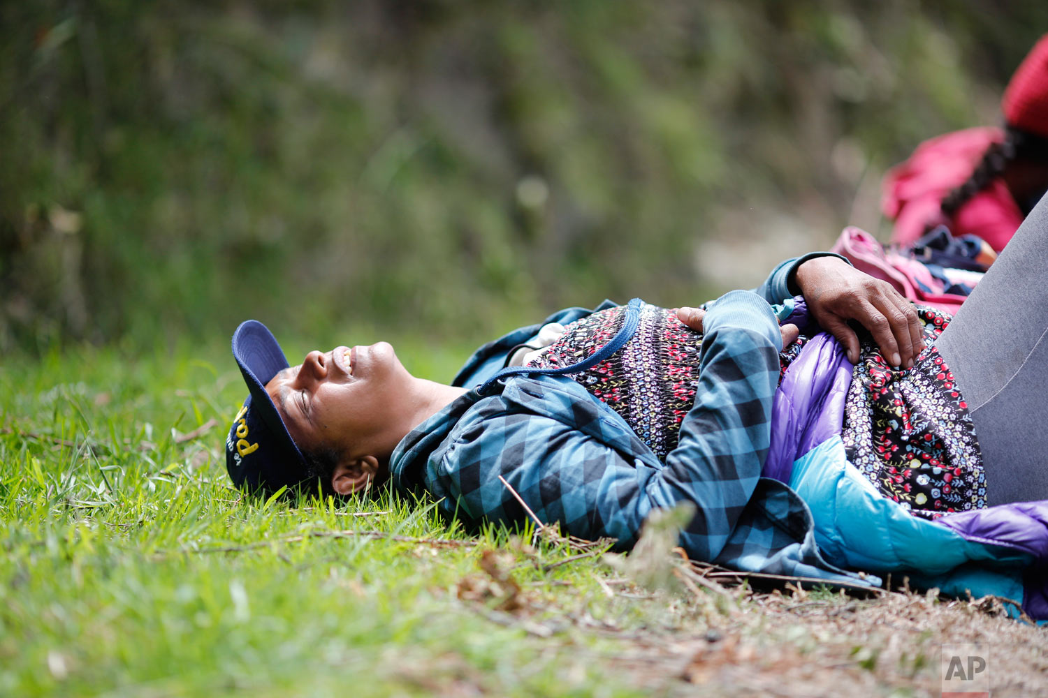  In this Sept 1, 2018 photo, fatigued Venezuelan Sandra Cadiz throws herself on the grass as she takes a break from walking to the Berlin paramo leading to the city of Bucaramanga, Colombia, on her journey to Peru. Like a growing number of desperate 