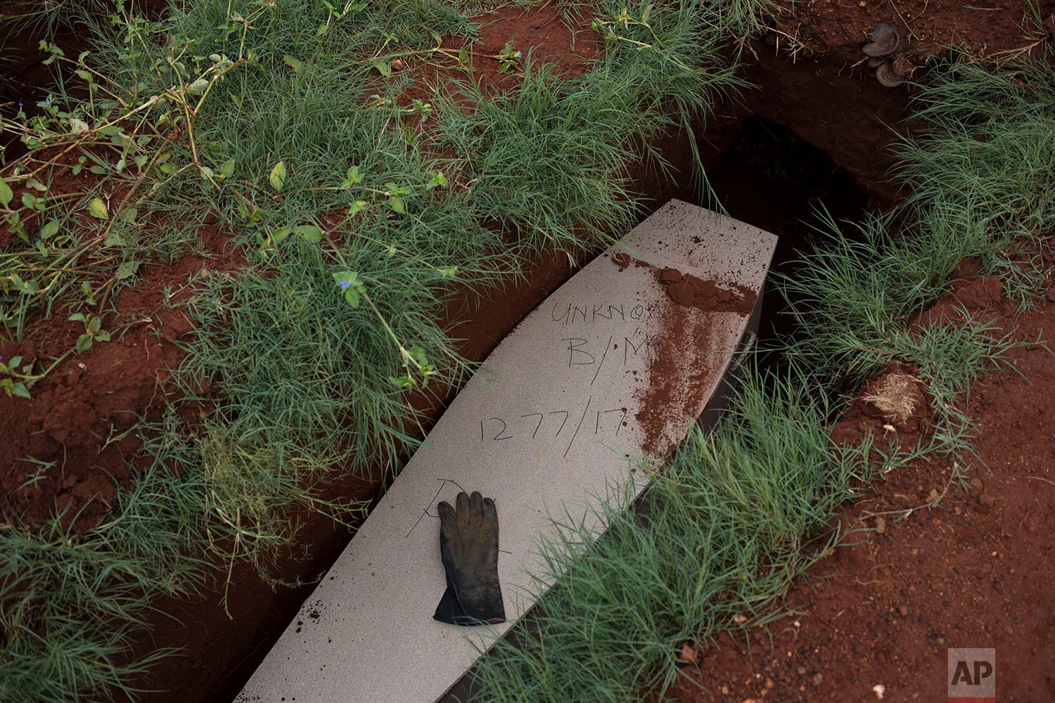 In this Thursday, April 12, 2018 photo, a glove sits on top of the coffin of an unidentified male at the Olifantsvlei cemetery outside Johannesburg. (AP Photo/Bram Janssen)