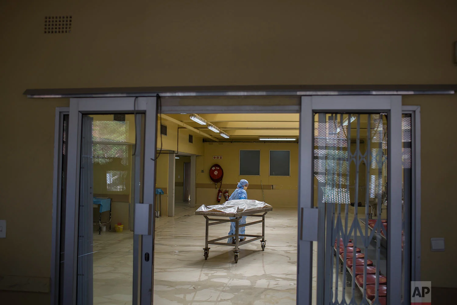 In this Wednesday, Jan. 24, 2018 photo, a forensic worker transports a body at a mortuary in Johannesburg. (AP Photo/Bram Janssen)