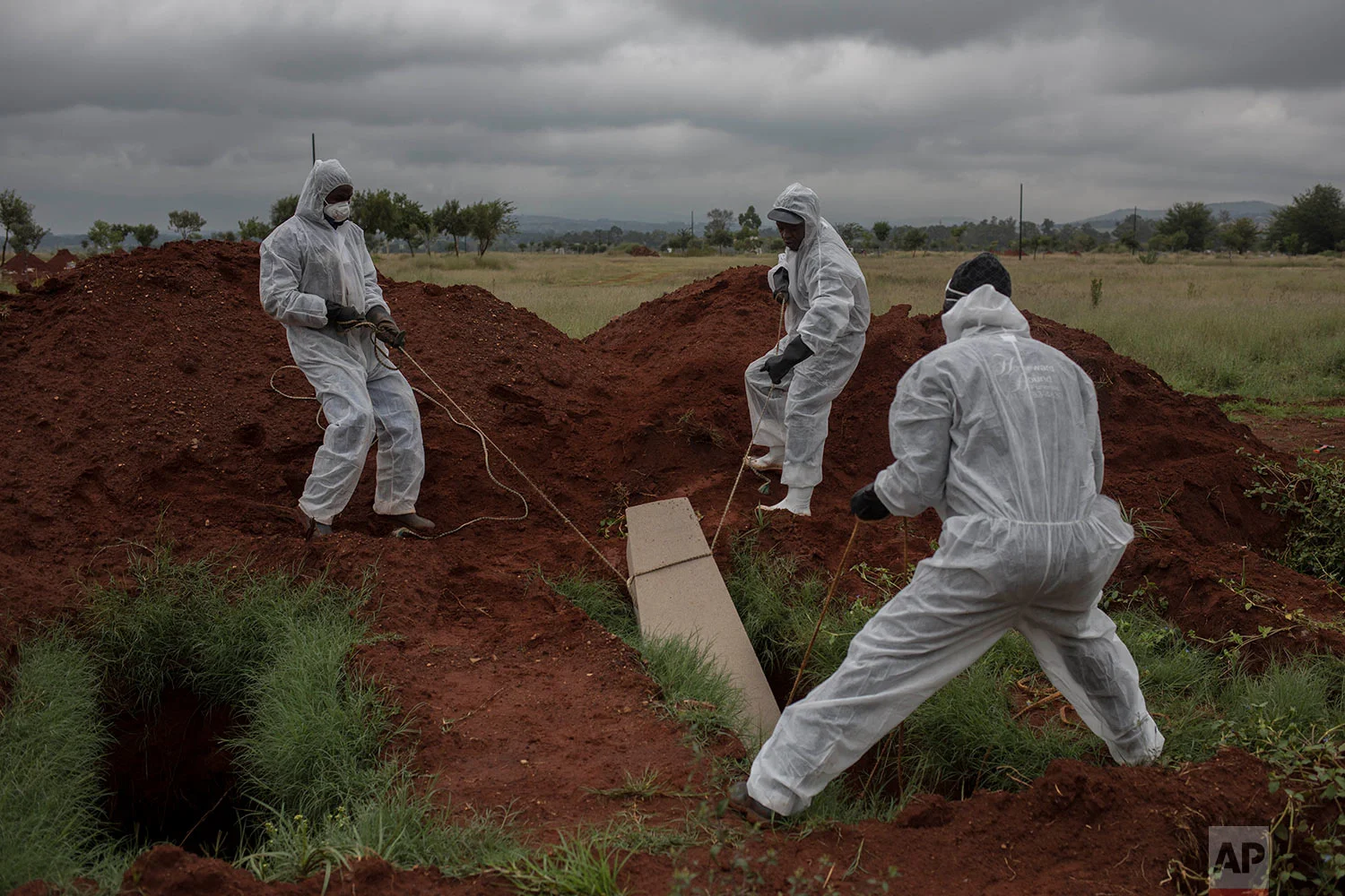 In this Thursday, April 12, 2018 photo, mortuary workers bury the coffin of an unidentified male at Olifantsvlei cemetery outside Johannesburg. (AP Photo/Bram Janssen)