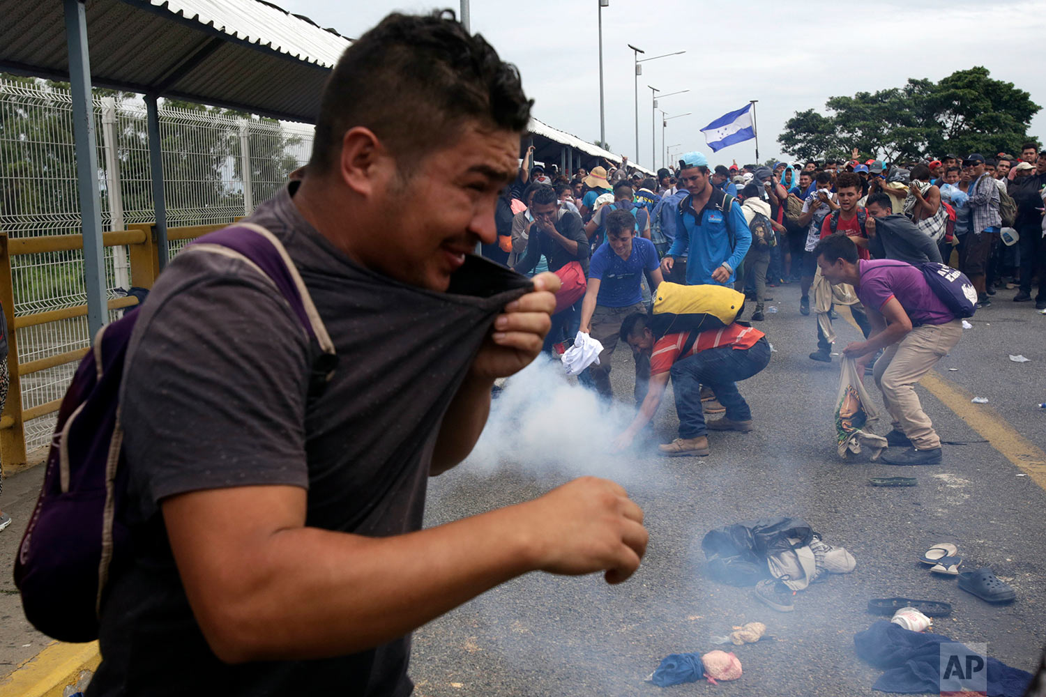  Men attempt to grab a tear gas canister thrown by the Mexican Federal Police, after Central American migrants rushed the gate at the border crossing in Ciudad Hidalgo, Mexico, Friday, Oct. 19, 2018. (AP Photo/Moises Castillo) 