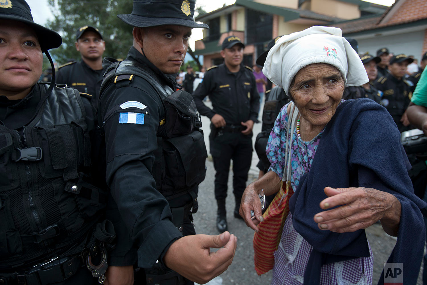  An elderly Honduran migrant woman talks with Guatemalan police who temporarily block the road to keep her and her caravan from advancing, in Esquipulas, Guatemala, Monday, Oct. 15, 2018. (AP Photo/Moises Castillo) 