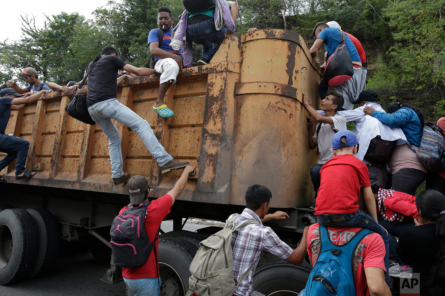  Honduran migrants bound to the U.S border climb into the bed of a truck in Zacapa, Guatemala, Wednesday, Oct. 17, 2018. (AP Photo/Moises Castillo) 