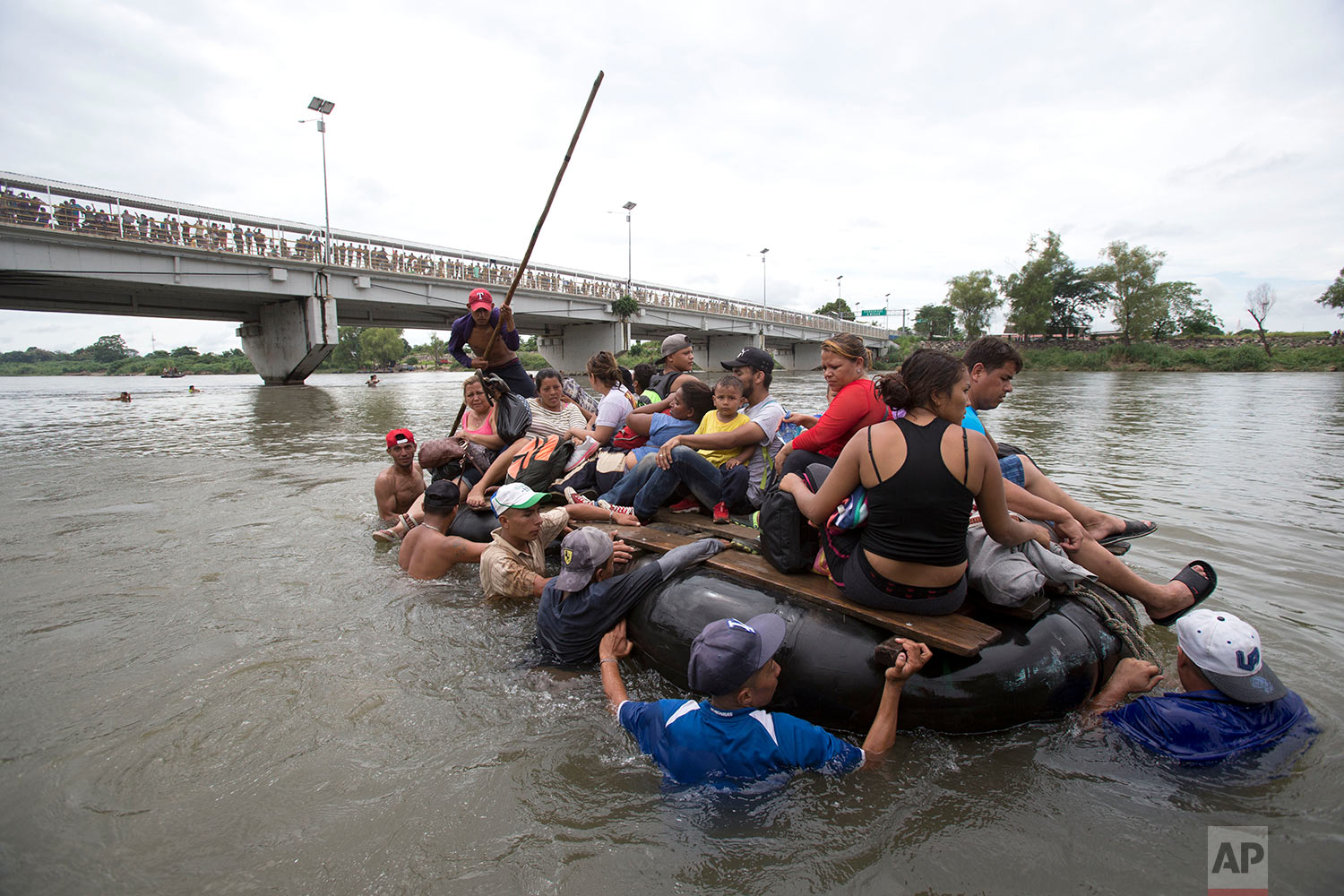 A group of Central American migrants cross the Suchiate River aboard a raft made out of tractor inner tubes and wooden planks, on the the border between Guatemala and Mexico, in Ciudad Hidalgo, Mexico, Saturday, Oct. 20, 2018. (AP Photo/Moises Casti