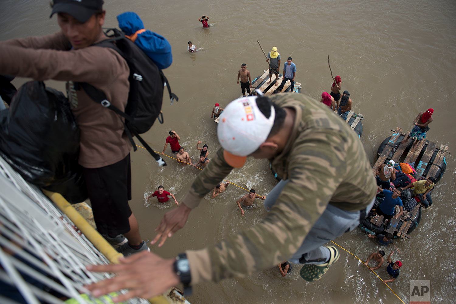  Migrants tired of waiting to cross into Mexico, jumped from a border bridge fence into the Suchiate River, in Tecun Uman, Guatemala, Friday, Oct. 19, 2018. (AP Photo/Oliver de Ros) 