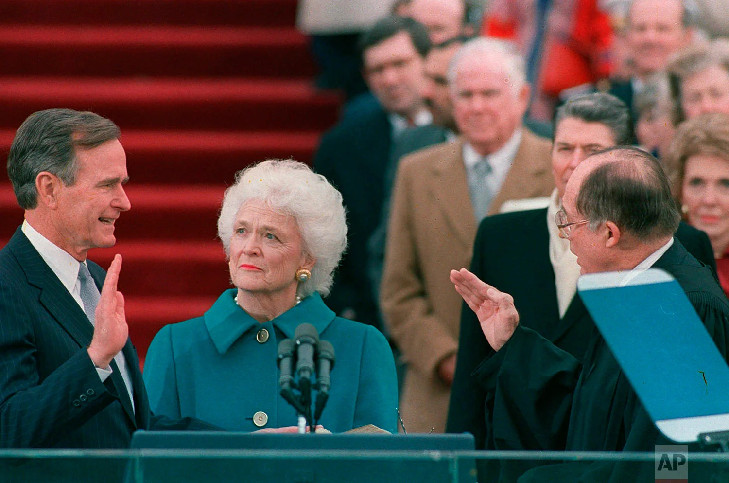 President George H.W. Bush raises his right hand as he is sworn into office as the 41st president of the United States by Chief Justice William Rehnquist outside the west front of the Capitol on Jan. 20, 1989. First lady Barbara Bush holds the bible for her husband. (AP Photo/Bob Daugherty)