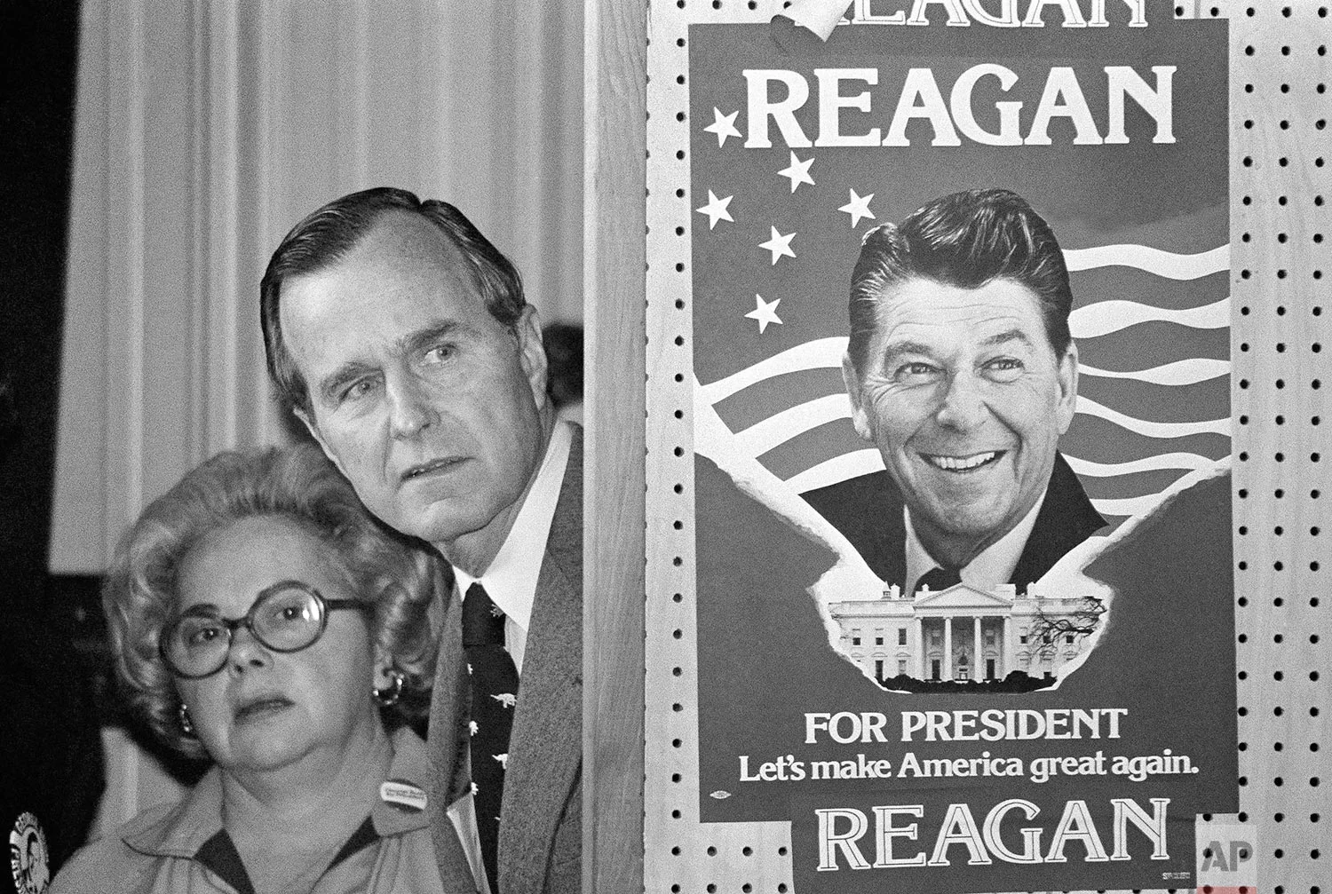 George Bush and an unidentified woman peek around a partition with a poster of Ronald Reagan, one of his opponents for the Republican party presidential nomination, before he speaks on March 4, 1980, in Columbia, S.C. (AP Photo)