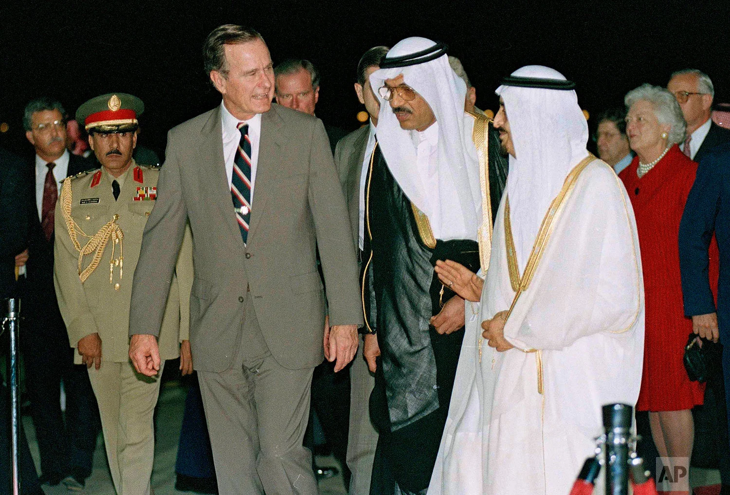 President George Bush is greeted by King Fahd as he arrives in Saudi Arabia, Nov. 21, 1990. At right is first lady Barbara Bush. At center is an interpreter. (AP Photo/J. Scott Applewhite)