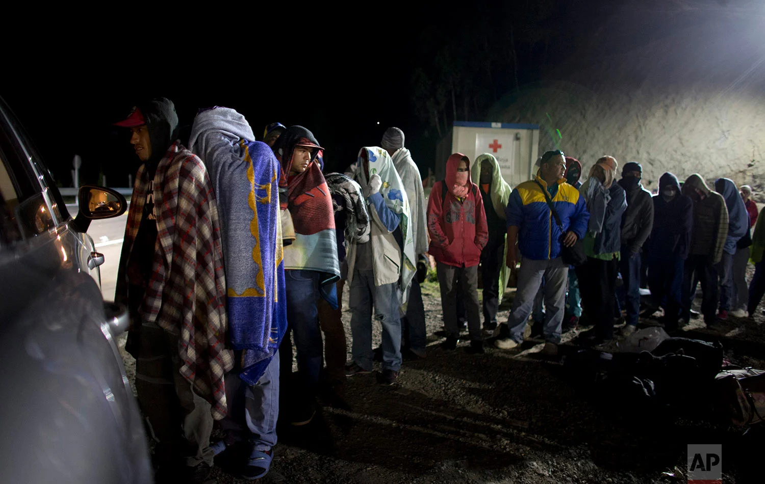 In this Friday, Aug. 31, 2018 photo, Venezuelan migrants line up for free bread and coffee, donated by a Colombian family from their car, at a gas station in Pamplona, Colombia. (AP Photo/Ariana Cubillos)