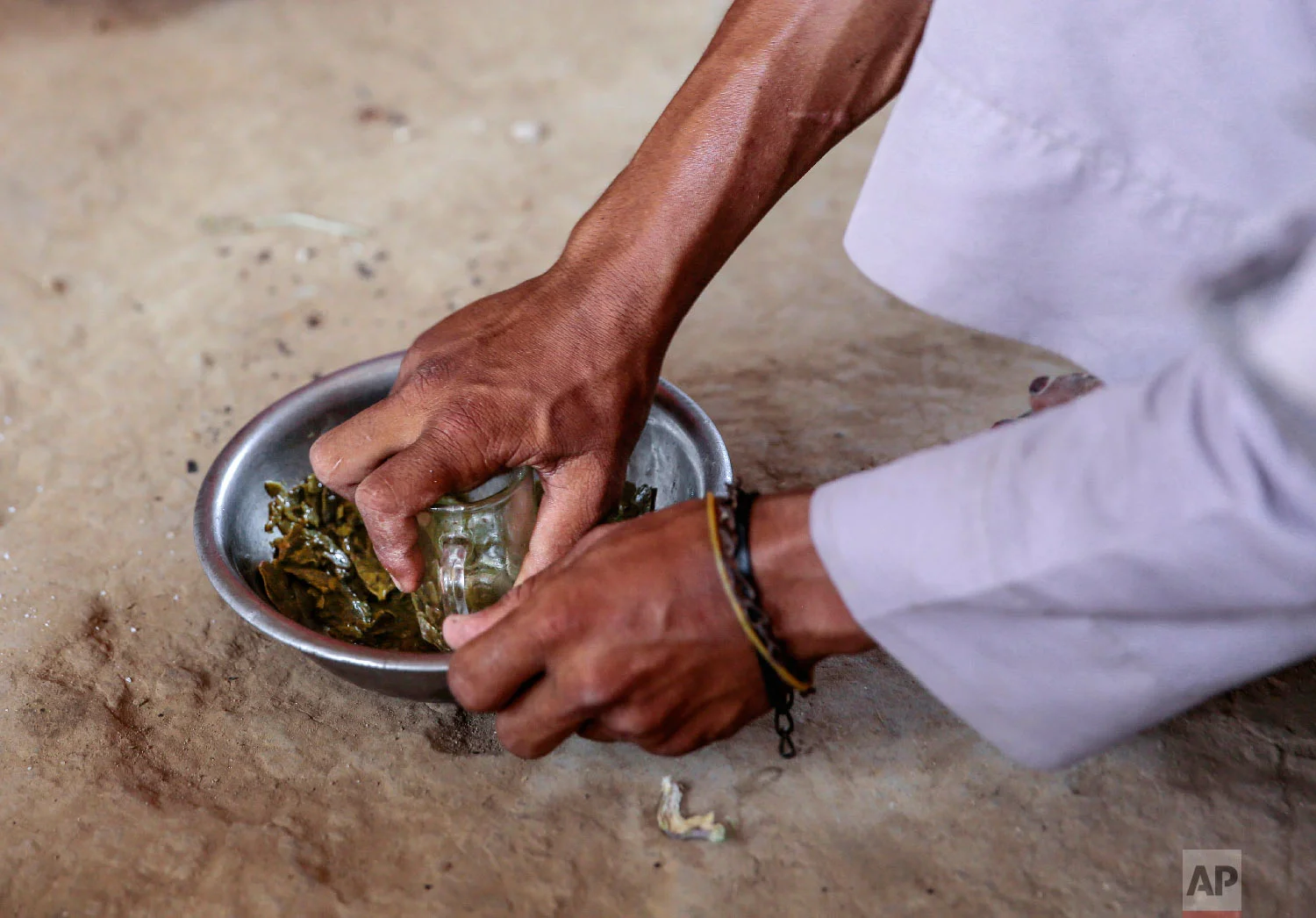A man prepares Halas for his children, a climbing vine of green leaves, in Aslam, Hajjah, Yemen. The leaves are made into green paste and used to be a traditional side dish, but at times of extreme poverty, it becomes the main meal. (AP Photo/Hani Mohammed)