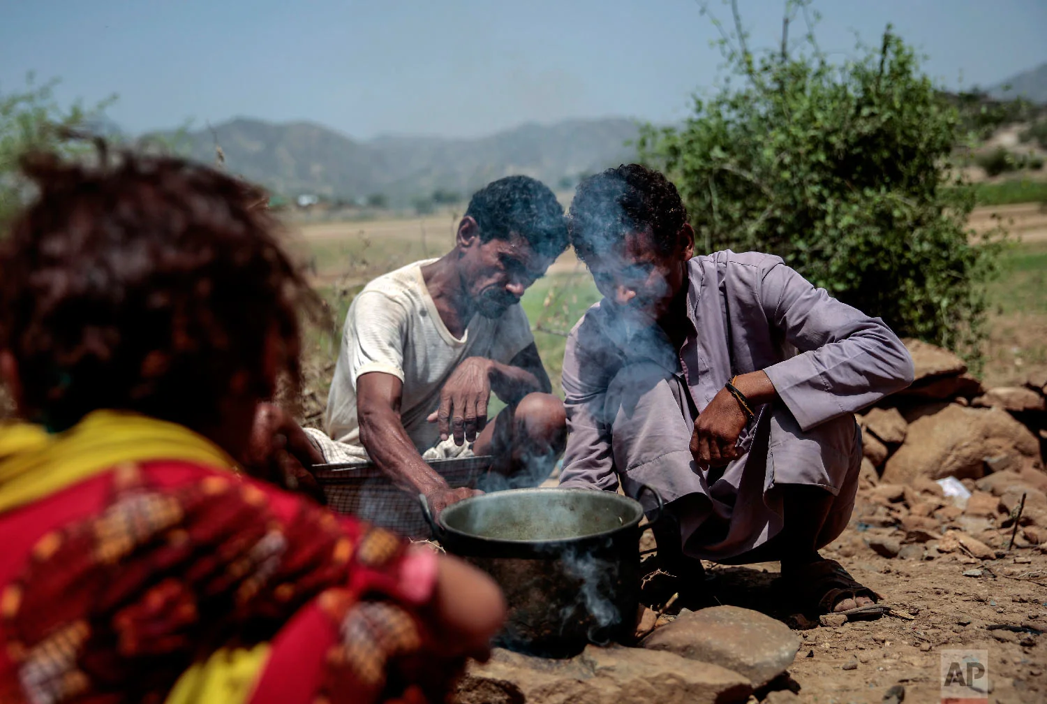 Men cook Halas for their children, a climbing vine of green leaves, in Aslam, Hajjah, Yemen. The leaves are made into green paste and used to be a traditional side dish, but at times of extreme poverty, it becomes the main meal. (AP Photo/Hani Mohammed)