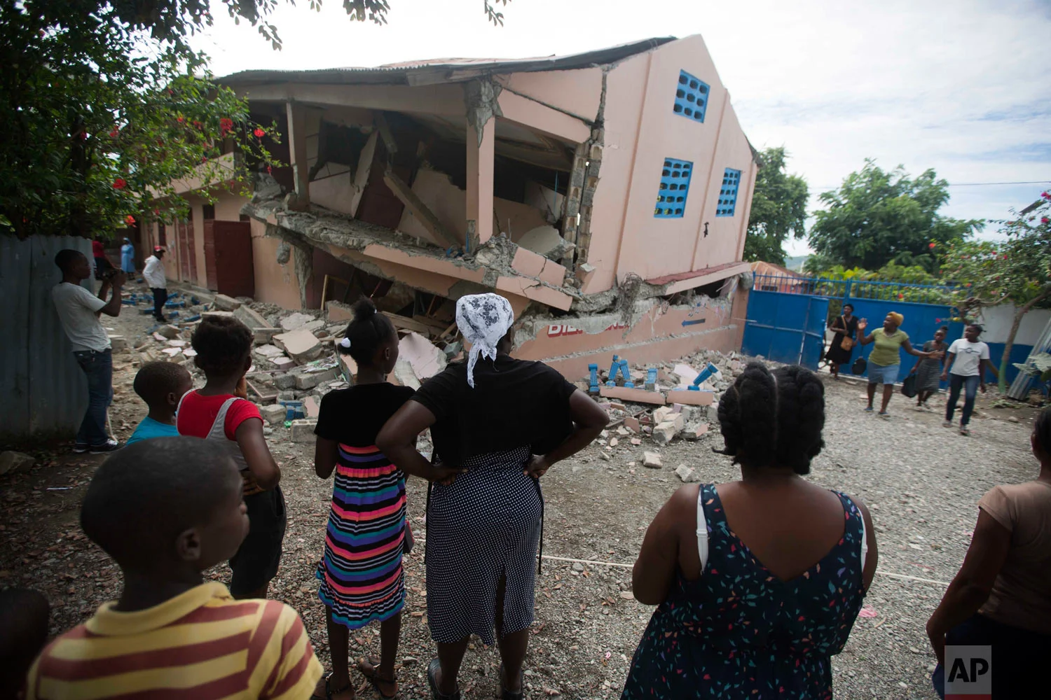 Residents look at a collapsed school after a magnitude 5.9 earthquake hit the night before in Gros Morne, Haiti, Oct. 7, 2018. The quake killed at least 11 people and left dozens injured. (AP Photo/Dieu Nalio Chery)