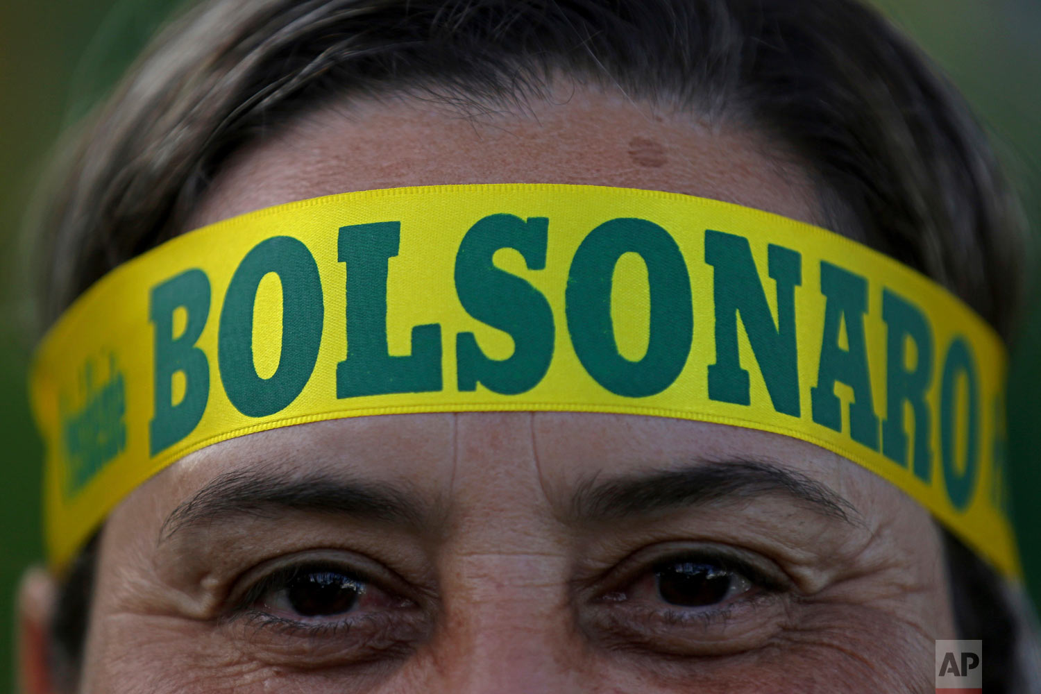  A supporter of presidential front-runner Jair Bolsonaro wears a headband supporting his candidate as he waits with others for election results outside the National Congress in Brasilia, Brazil, Oct. 28, 2018. Brazilian voters decide who will next le