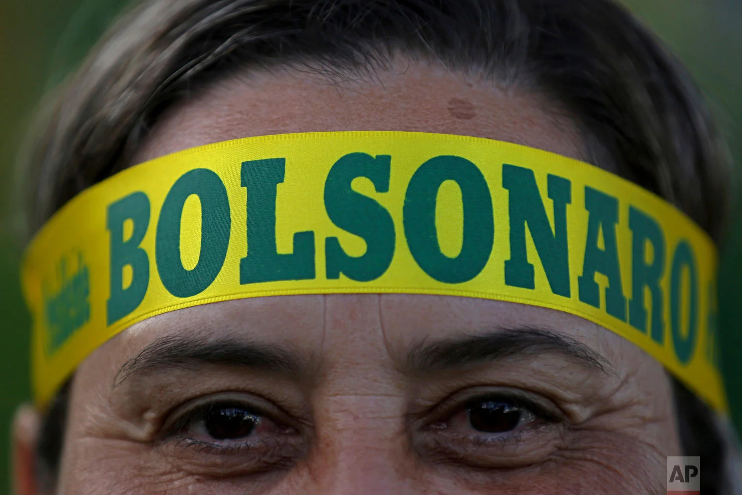 A supporter of presidential front-runner Jair Bolsonaro wears a headband supporting his candidate as he waits with others for election results outside the National Congress in Brasilia, Brazil, Oct. 28, 2018. Brazilian voters decide who will next lead the world's fifth-largest country, the left-leaning Fernando Haddad of the Workers' Party, or right-leaning rival Bolsonaro of the Social Liberal Party. (AP Photo/Eraldo Peres)