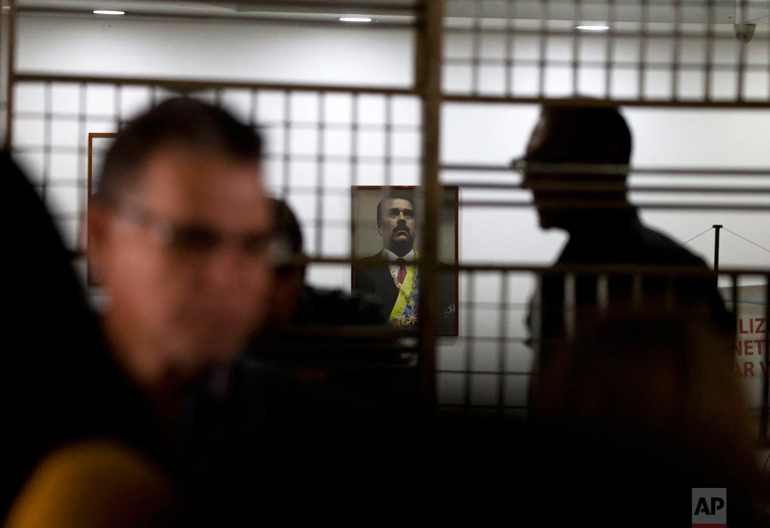 An image of Venezuela's President Nicolas Maduro hangs above the main desk at the Labor Ministry as workers demanding better wages protest outside the building, in Caracas, Venezuela, Oct. 5, 2018. (AP Photo/Fernando Llano)
