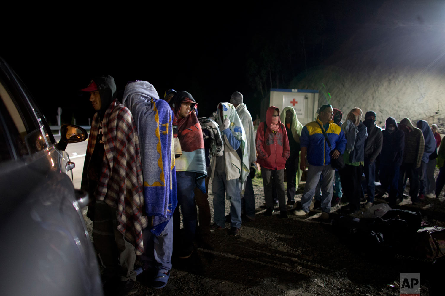  In this Aug. 31, 2018 photo published in October, Venezuelan migrants line up for free bread and coffee donated by a Colombian family from their car, at a gas station in Pamplona, Colombia. Millions have fled Venezuela's deadly shortages and spirali