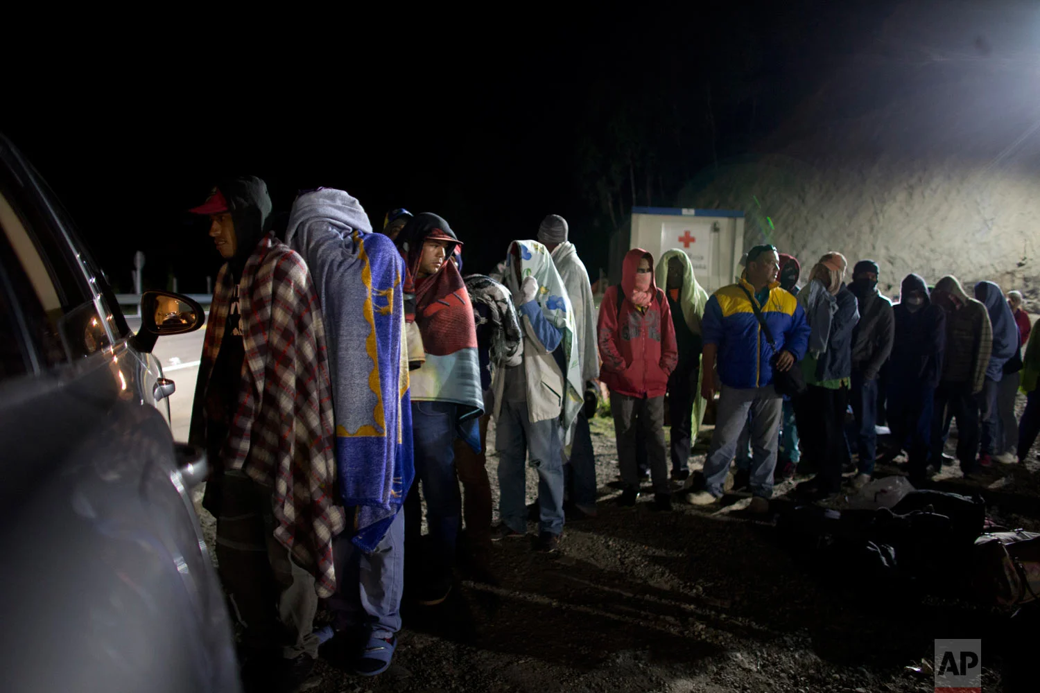 In this Aug. 31, 2018 photo published in October, Venezuelan migrants line up for free bread and coffee donated by a Colombian family from their car, at a gas station in Pamplona, Colombia. Millions have fled Venezuela's deadly shortages and spiraling hyperinflation in an exodus that rivals even the European refugee crisis in numbers. (AP Photo/Ariana Cubillos)