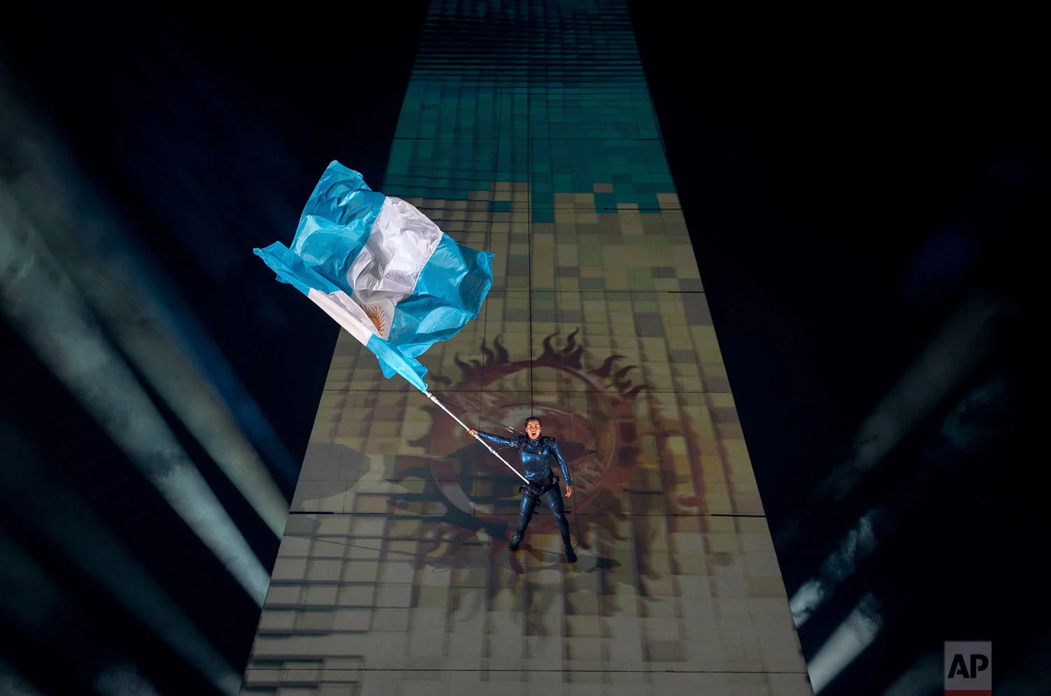 In this photo provided by the OIS/IOC, a performer repelling from the Obelisk of Buenos Aires holds the Argentine national flag at the start of the Youth Olympic Summer Games opening ceremony, in Buenos Aires, Argentina, Oct. 6, 2018. Over 4,000 of the world’s best young athletes between the ages of 15 to 18 are in the Argentinian capital for the third edition of the Youth Olympic Summer Games, the first time in Olympic history that an equal number of male and female athletes are competing in the youth games. (Florian Eisele/OIS/IOC via AP)