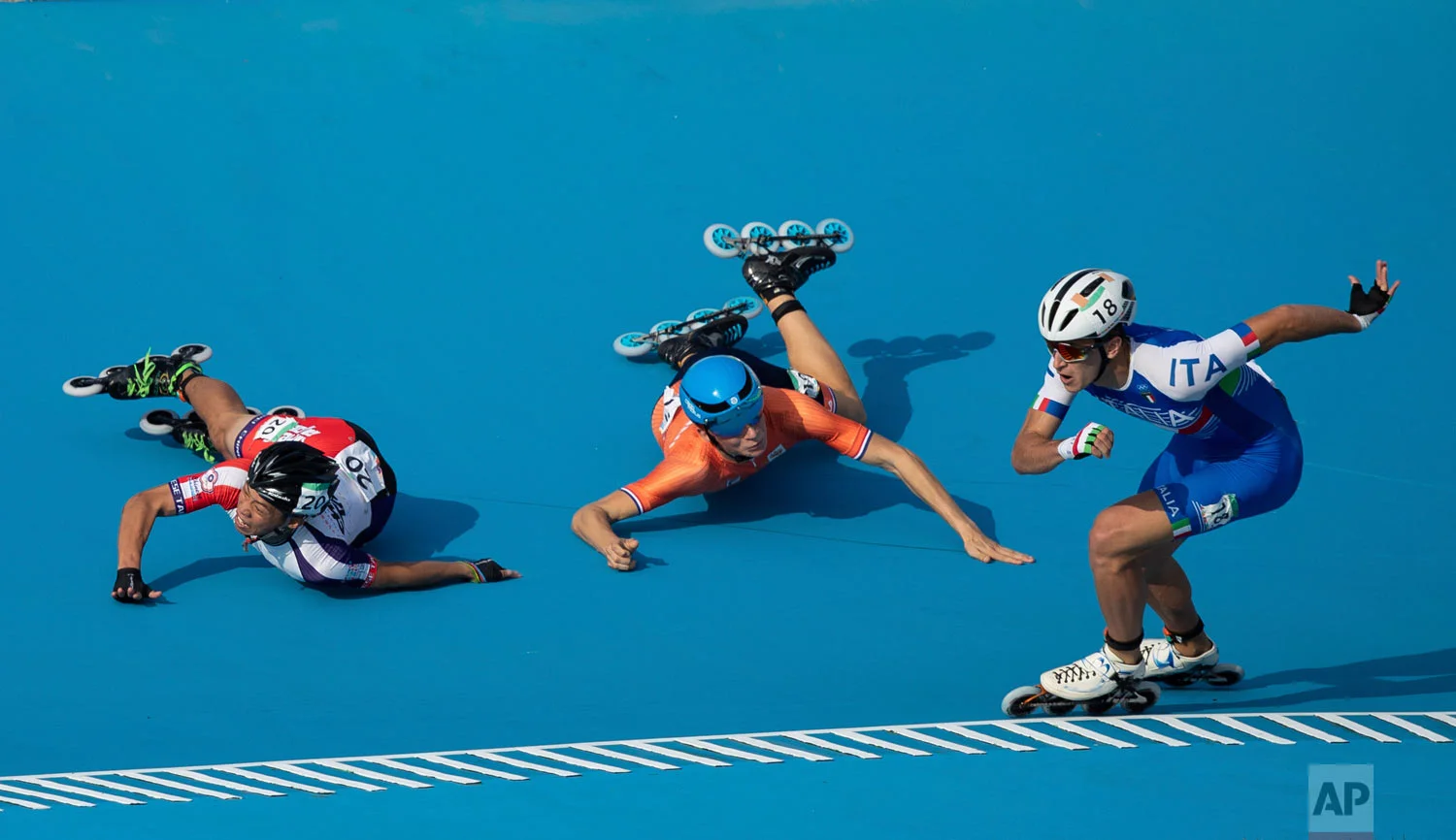 In this photo provided by the OIS/IOC, Italy's Vincenzo Maiorca takes the lead as Taiwan's Chiawei Chang, center, and The Netherland's Merijn Scheperkamp fall during the Roller Speed Skating Men's Combined Speed Event during the Youth Olympic Games in Buenos Aires, Argentina, Monday, Oct. 8, 2018. (Simon Bruty/OIS/IOC via AP)
