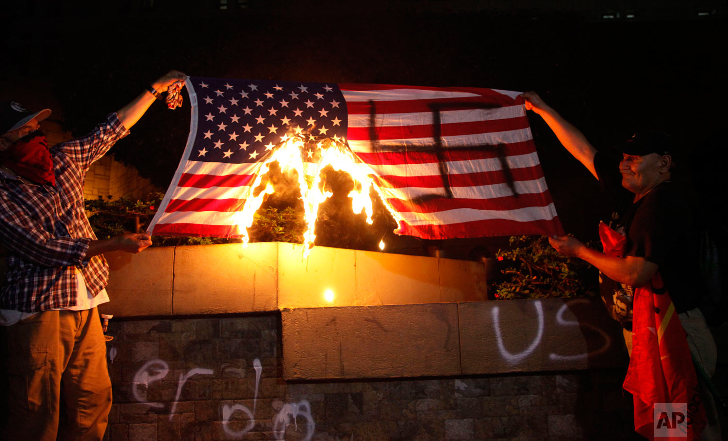  People burn a U.S. flag outside the U.S. embassy to protest in favor of the migrant caravan stuck on the Guatemala-Mexico border, in Tegucigalpa, Honduras, Oct. 19, 2018. (AP Photo/Fernando Antonio) 