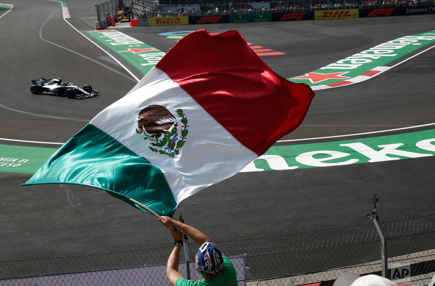  Mercedes driver Lewis Hamilton, from Britain, drives in a practice run for the upcoming Formula One Mexico Grand Prix auto race, as a fan waves a Mexican flag at the Hermanos Rodriguez racetrack in Mexico City, Oct. 26, 2018. (AP Photo/Marco Ugarte)