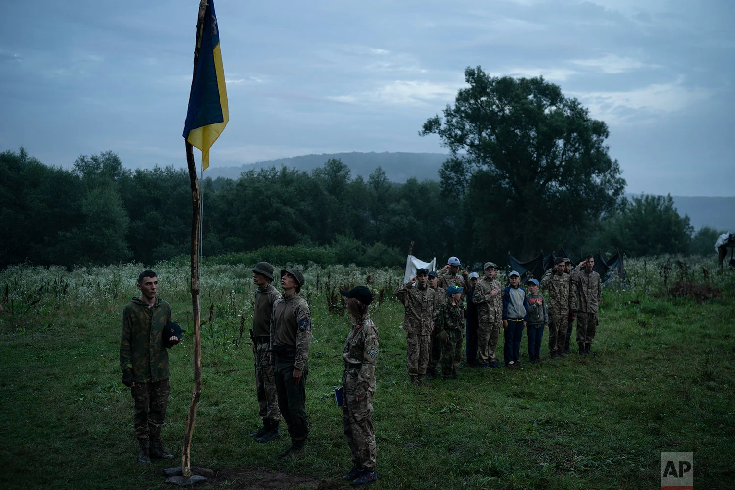 Young participants and instructors of the "Temper of will" summer camp, organized by the nationalist Svoboda party, stand in formation as they sing the national anthemn on July 28, 2018, in a village near Ternopil, Ukraine. Earlier this year, the Ministry of Youth and Sports earmarked 4 million hryvnias (about $150,000) to fund some of the youth camps among the dozens built by the nationalists. (AP Photo/Felipe Dana)
