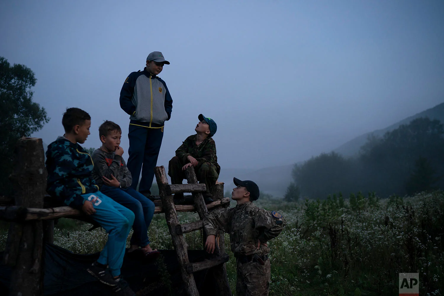 Young participants of the "Temper of will" summer camp, organized by the nationalist Svoboda party, gather in-between exercises on July 27, 2018, in a village near Ternopil, Ukraine. (AP Photo/Felipe Dana)