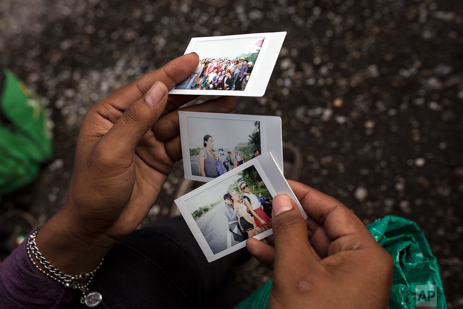  In this Nov. 3, 2018 photo, a member of a group of about 50 LGBTQ migrants traveling with the caravan hoping to reach the U.S. border, looks at polaroids taken by a colleague who is documenting their journey, on the road to Sayula, Mexico. (AP Photo