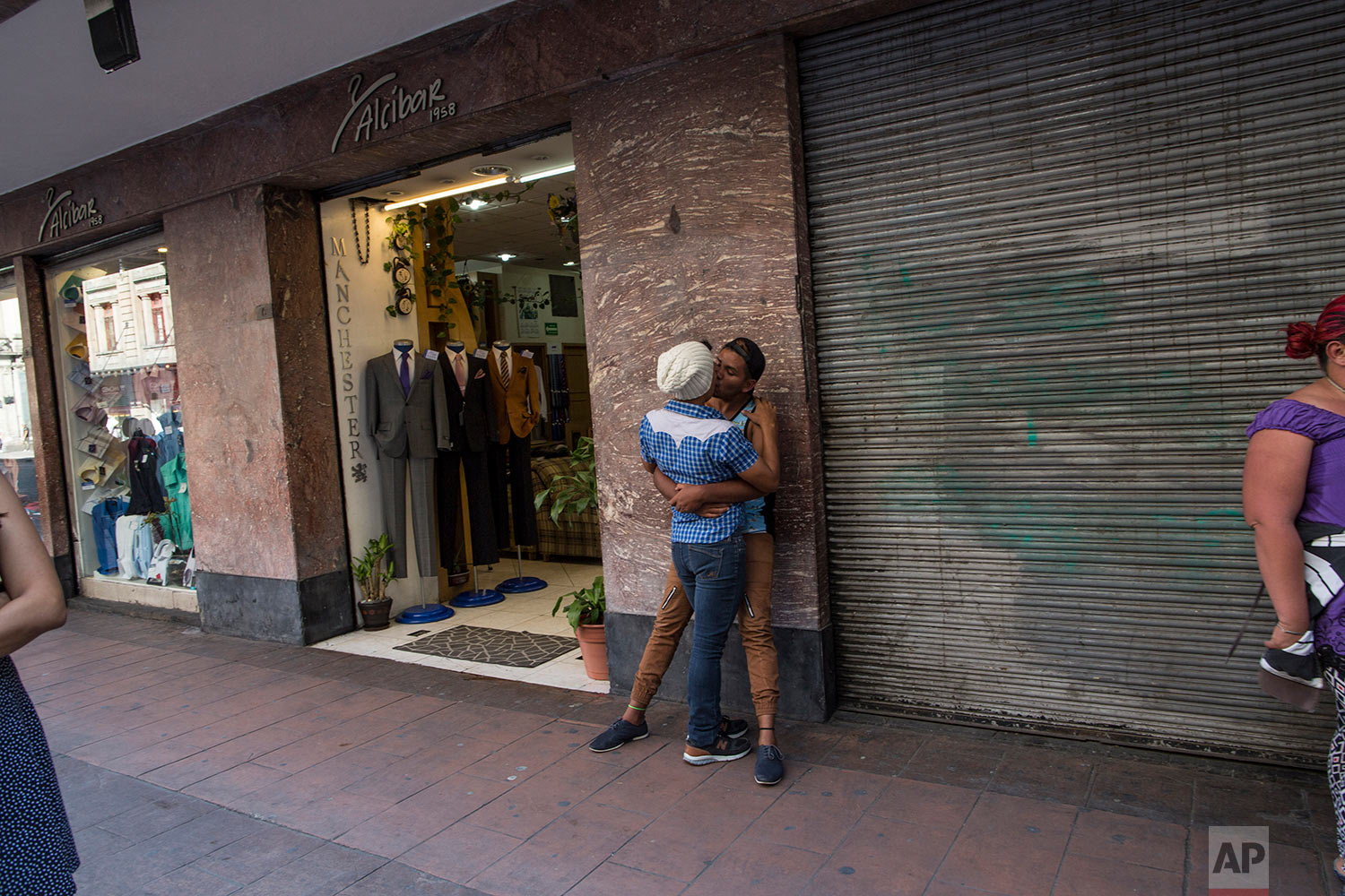  In this Nov. 8, 2018 photo, a couple who is part of a group of 50 or so LGBTQ migrants traveling with the migrant caravan hoping to reach the U.S. border, share a kiss while taking in the sites during a rest day in Mexico City. (AP Photo/Rodrigo Abd