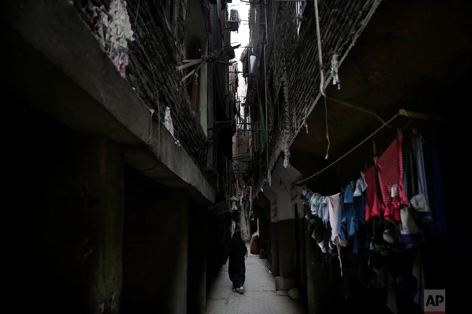 In this Oct. 29, 2018 photo, a woman walks in between buildings in the Imbaba neighborhood of Giza, Egypt. (AP Photo/Nariman El-Mofty)
