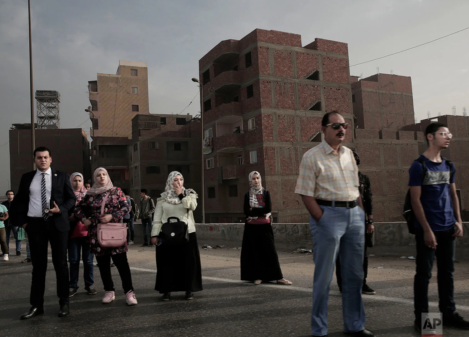 In this Oct. 23, 2018 photo, people wait for a bus on the ring road early morning, in Cairo, Egypt. (AP Photo/Nariman El-Mofty)