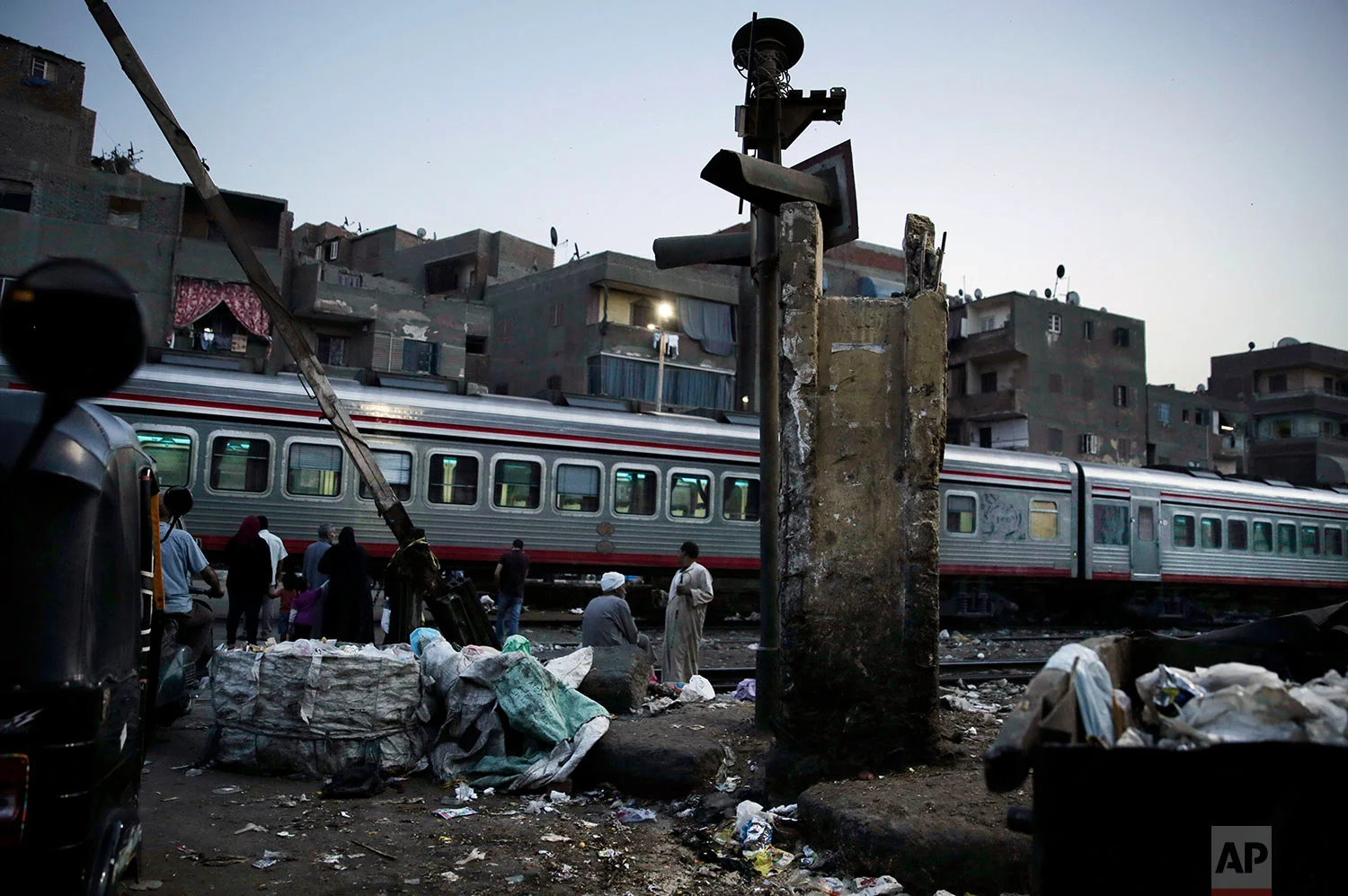 In this Oct. 23, 2018 photo, people wait for the train to pass in Shubra, Cairo, Egypt. (AP Photo/Nariman El-Mofty)