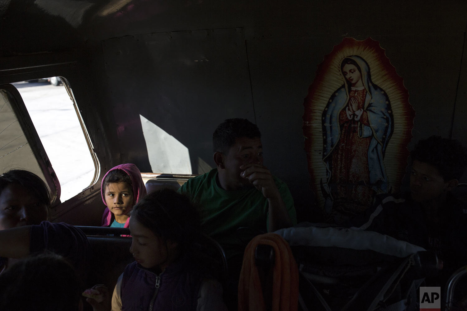 Genesis Mejia, 7, who is part of the Central American caravan hoping to reach the U.S. border, sits inside a bus in La Concha, Mexico, Wednesday, Nov. 14, 2018. Buses and trucks are carrying some migrants into the state of Sinaloa along the Gulf of California and further northward into the border state of Sonora. The bulk of the main caravan appeared to be about 1,100 miles from the border, but was moving hundreds of miles per day. At right is an image of the Virgin of Guadalupe. (AP Photo/Rodrigo Abd)