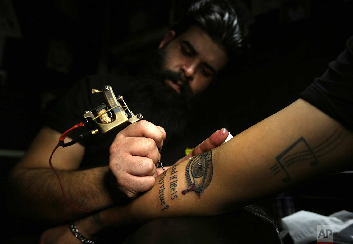  In this Tuesday. Oct. 23, 2018, photo, a man gets a tattoo on his arm in a tattoo studio in Baghdad, Iraq. One tattoo shop owner said he receives an average of 20 persons a year who want to cover their scars with tattoos, a nearly 30 percent increas