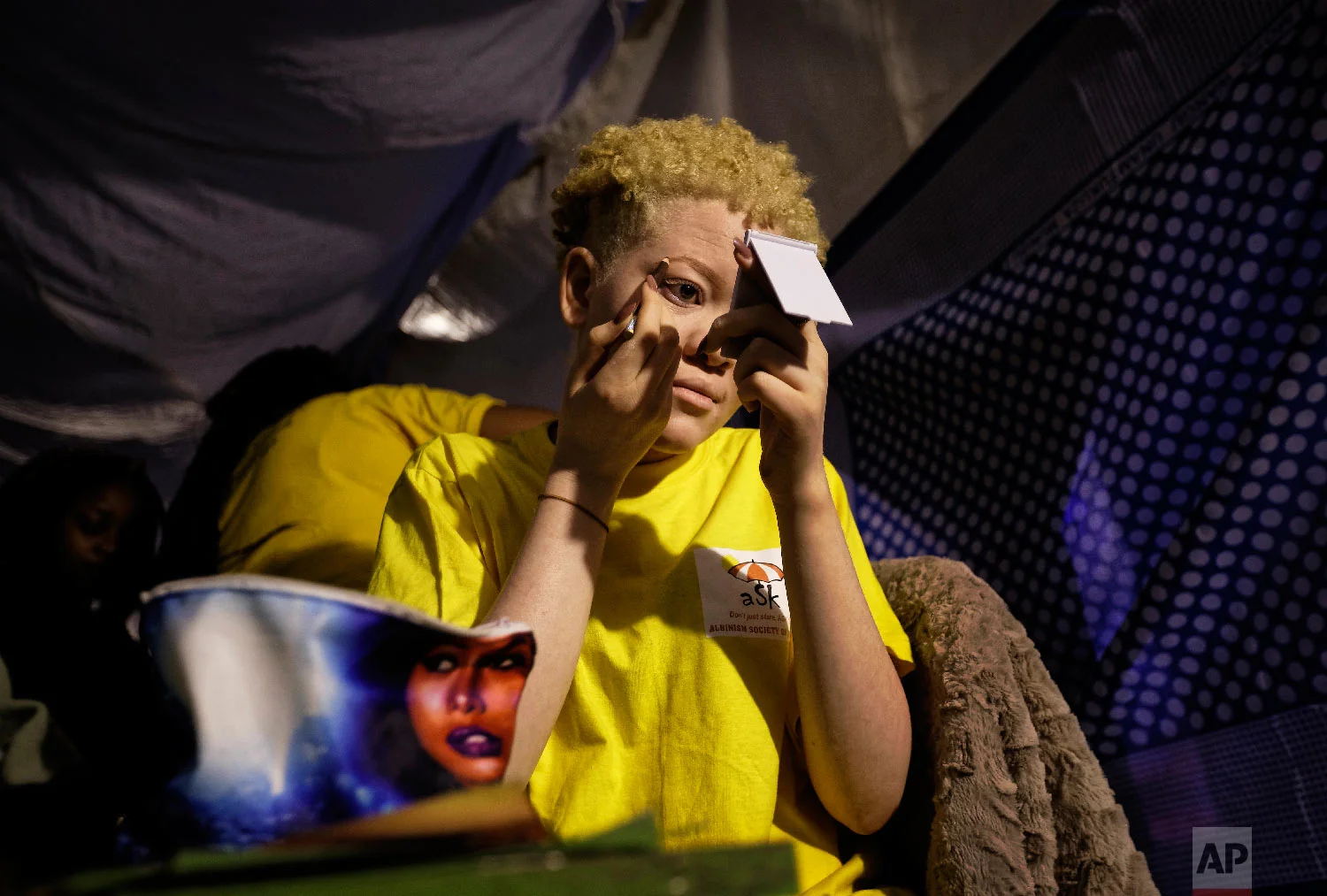 Kenyan contestant Lucianah Nyawira, 21, does her makeup as she prepares to perform in the Mr. & Miss Albinism East Africa contest, organized by the Albinism Society of Kenya, in Nairobi, Kenya, Nov. 30, 2018. (AP Photo/Ben Curtis)