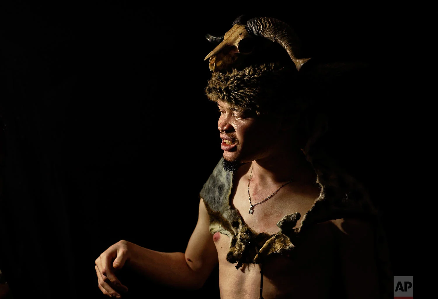A contestant wears a traditional costume including animal hides and a skull, as he prepares to perform in the "Mr. & Miss Albinism East Africa" contest, organized by the Albinism Society of Kenya, in Nairobi, Kenya on Nov. 30, 2018. (AP Photo/Ben Curtis)