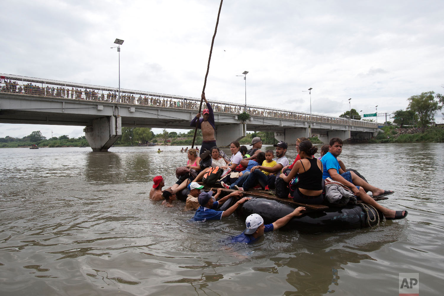  A group of Central American migrants cross the Suchiate River aboard a raft made out of tractor inner tubes and wooden planks, on the the border between Guatemala and Mexico, in Ciudad Hidalgo, Mexico, Oct. 20, 2018. (AP Photo/Moises Castillo) 