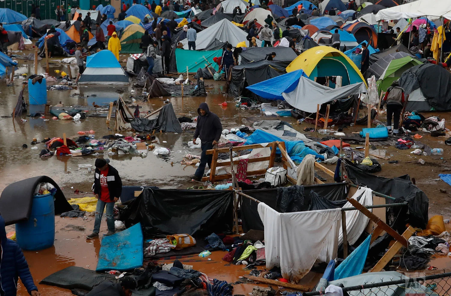 Migrants walk amidst flooded tents after heavy rains poured down on a sports complex sheltering thousands of Central Americans in Tijuana, Mexico, on Nov. 29, 2018. (AP Photo/Rebecca Blackwell)