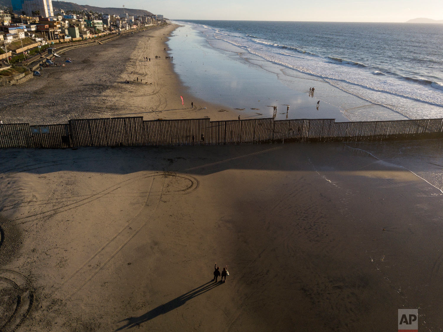  People on the U.S. side of the border wave at those on the Mexico side, at the border structure in San Diego on Nov. 23, 2018. (AP Photo/Rodrigo Abd) 