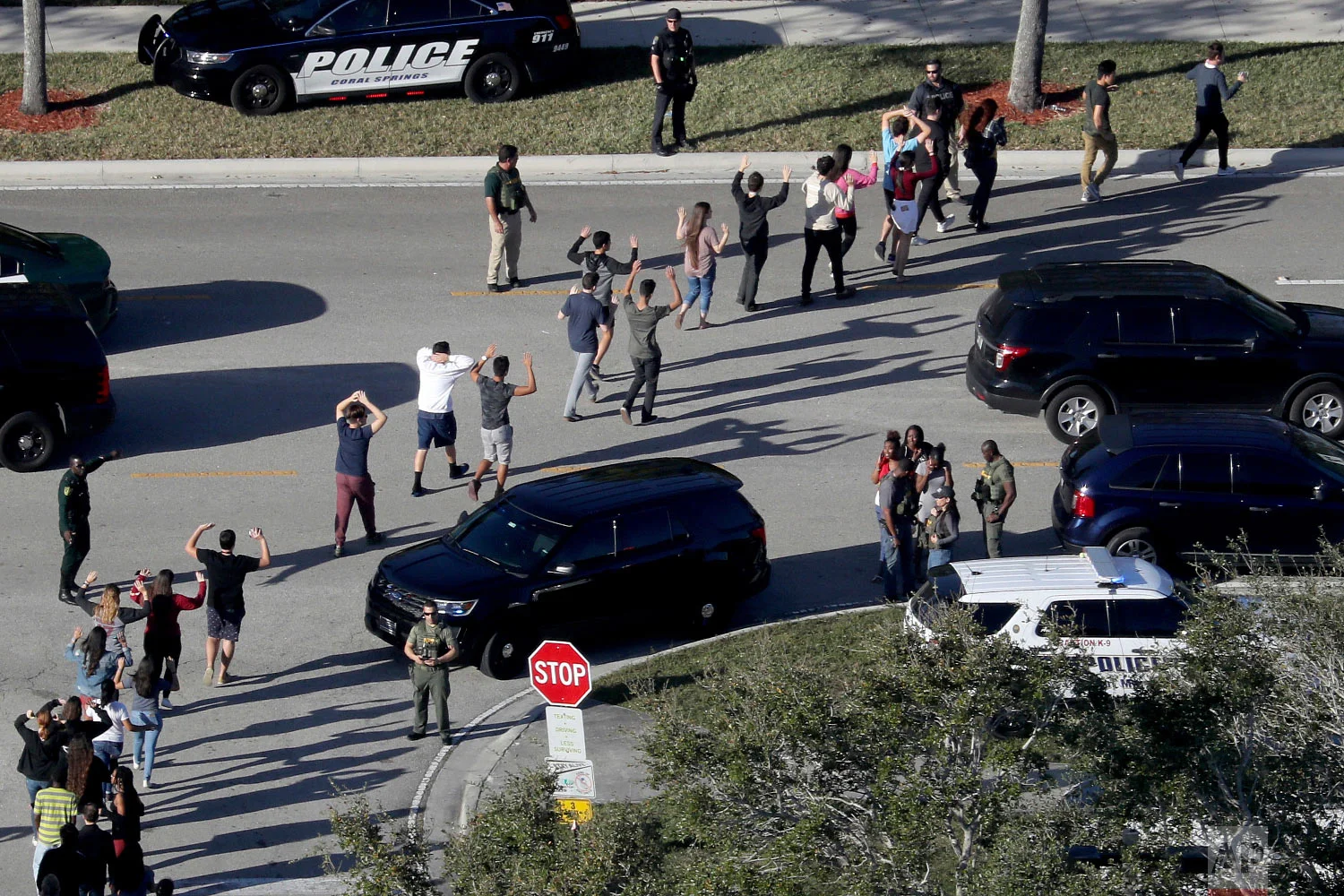 Students hold their hands in the air as they are evacuated by police from Marjory Stoneman Douglas High School in Parkland, Fla., on Feb. 14, 2018, after a shooter opened fire on the campus. (Mike Stocker/South Florida Sun-Sentinel via AP)