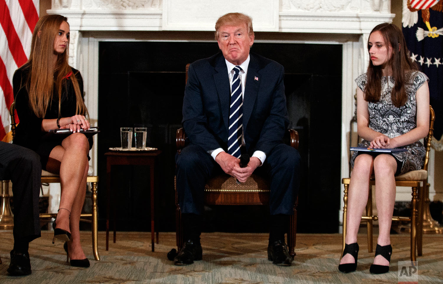  President Donald Trump, joined by Marjory Stoneman Douglas High School student Carson Abt, right, and Julia Cordover, the school's student body president, pauses during a listening session with high school students, teachers and others at the White 