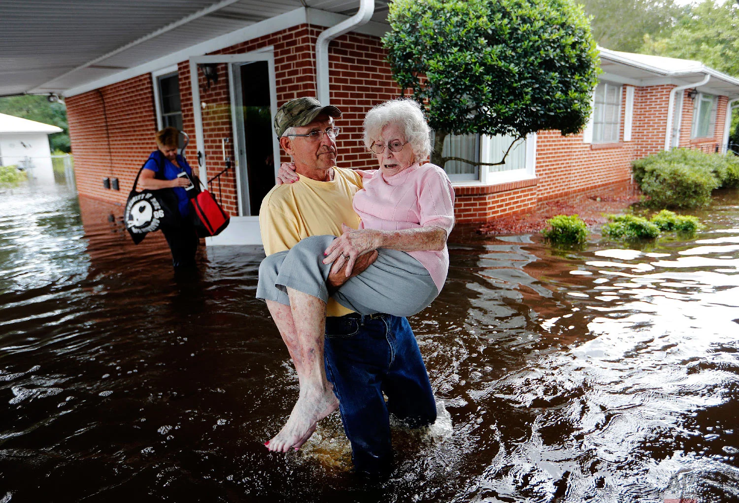 Bob Richling carries Iris Darden, 84, out of her flooded home as her daughter-in-law, Pam Darden, gathers her belongings in the aftermath of Hurricane Florence in Spring Lake, N.C. on Sept. 17, 2018. (AP Photo/David Goldman)