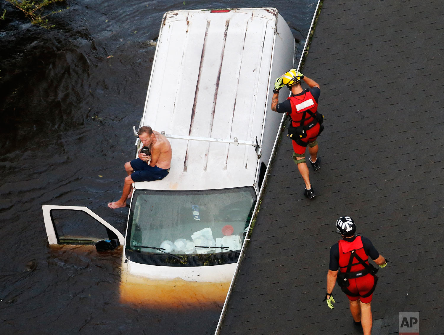  U.S. Coast Guard rescue swimmers Samuel Knoeppel, center, and Randy Haba, bottom right, approach Willie Schubert on a stranded van in Pollocksville, N.C., on Sept. 17, 2018, in the aftermath of Hurricane Florence. (AP Photo/Steve Helber) 