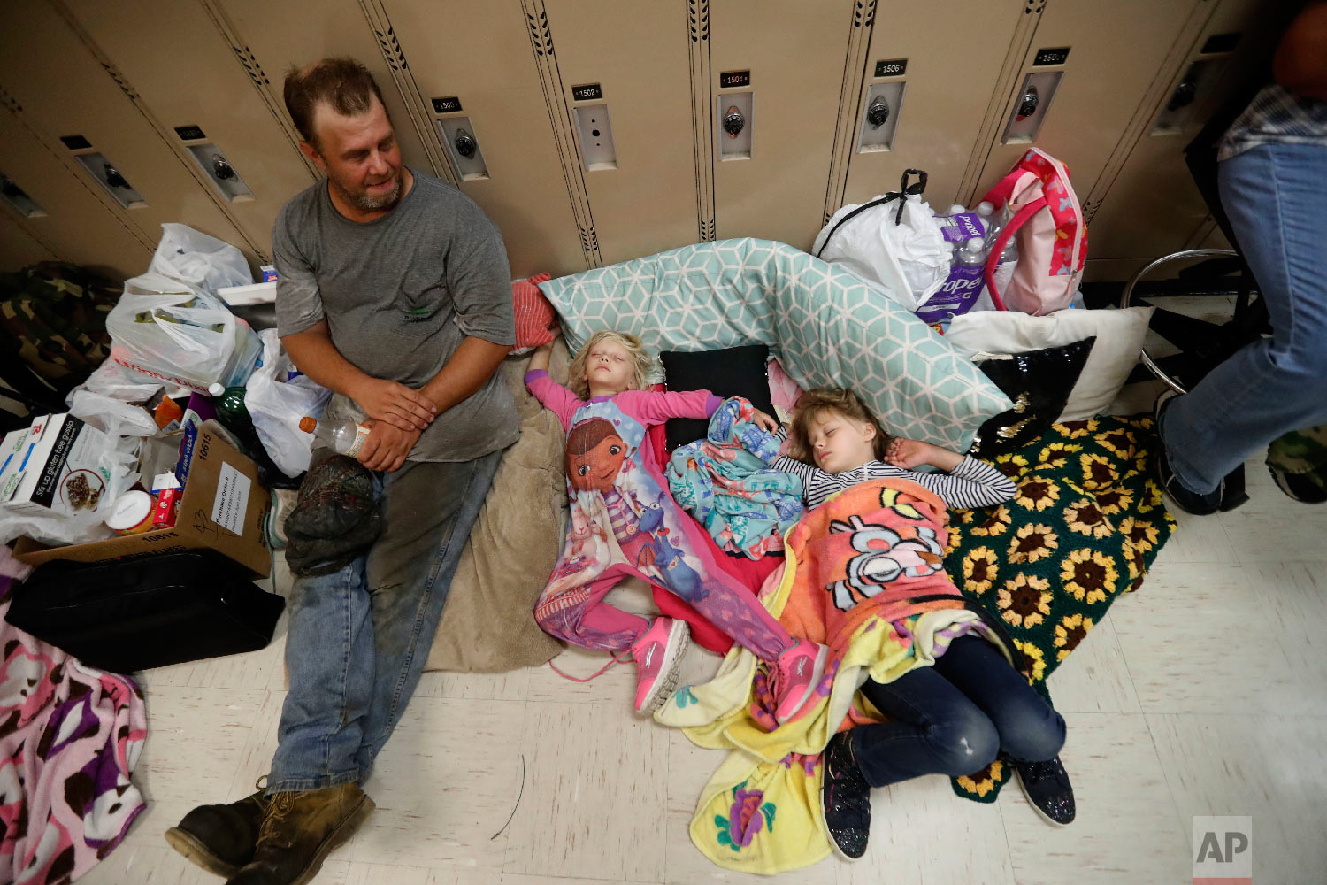  Earnest Sweet sits while his daughters Terri, 4, center, and Anna, 7, sleep at an evacuation shelter set up at Rutherford High School in Panama City Beach, Fla., in advance of Hurricane Michael, which is expected to make landfall on Oct. 10, 2018. (