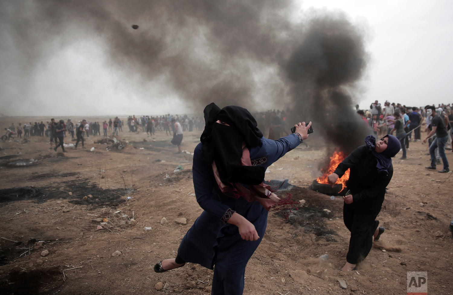  Palestinian women hurl stones at Israeli troops during a protest at the Gaza Strip's border with Israel on May 4, 2018. (AP Photo/ Khalil Hamra) 
