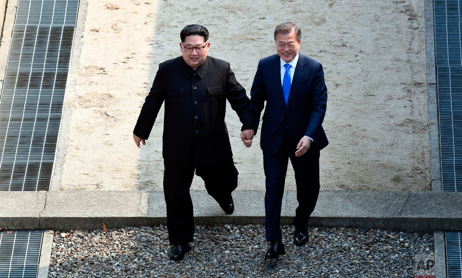  North Korean leader Kim Jong Un, left, and South Korean President Moon Jae-in cross the military demarcation line at the border village of Panmunjom in Demilitarized Zone on April 27, 2018. (Korea Summit Press Pool via AP) 