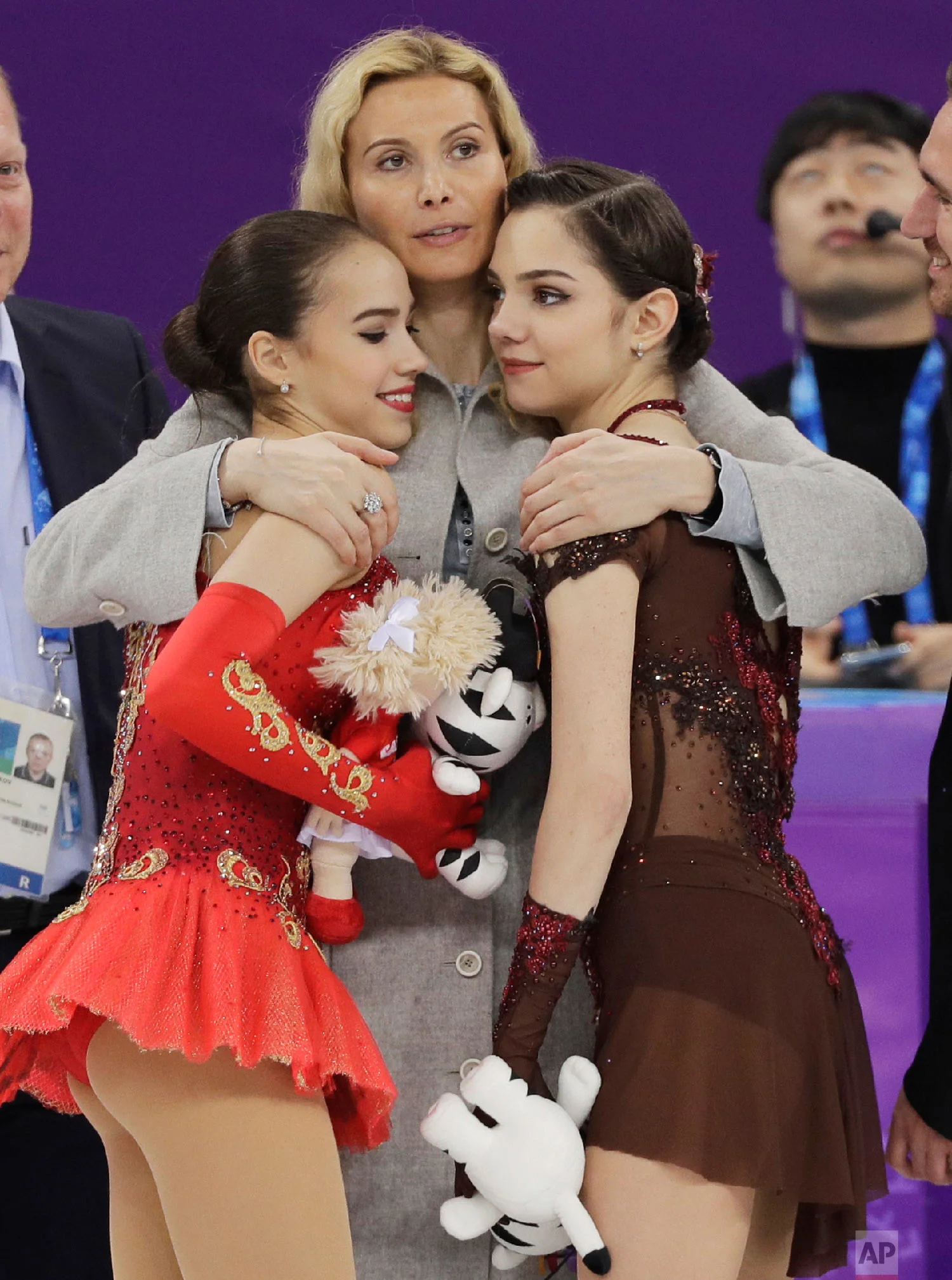 Gold medalist Alina Zagitova, left, and silver medalist Evgenia Medvedeva, both representing the Olympic Athletes of Russia (OAR), are embraced by their coach, Eteri Georgievna Tutberidze, at the women's free figure skating final at the 2018 Winter Olympics in Gangneung, South Korea, on Feb. 23, 2018.(AP Photo/David J. Phillip)