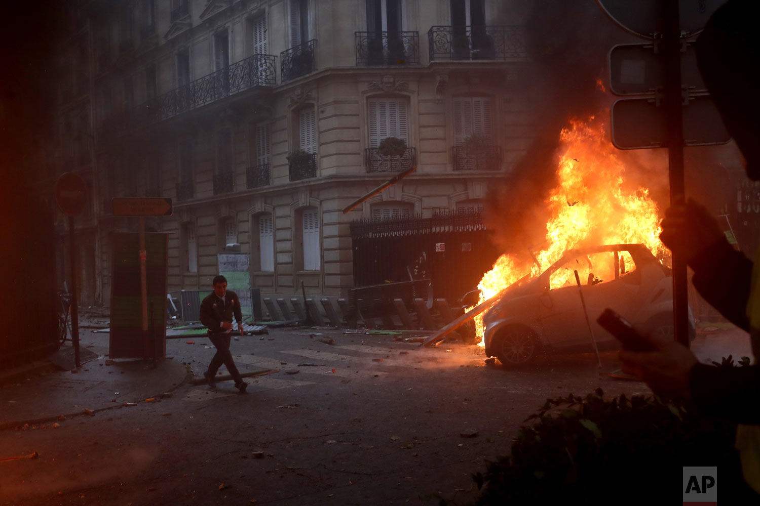  A demonstrator runs past a burning car during a demonstration in Paris on Saturday, Dec. 1, 2018, against an increase in fuel taxes. Even proponents of carbon taxes acknowledge that an increase in fuel taxes can disproportionally hurt low-income peo